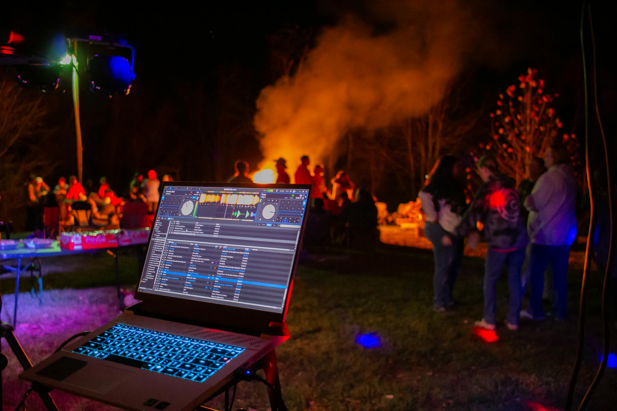 Vibrant outdoor night party scene featuring a DJ setup and blazing bonfire in West Virginia.